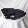 Contoured memory-foam blackout sleep mask resting on white fabric
